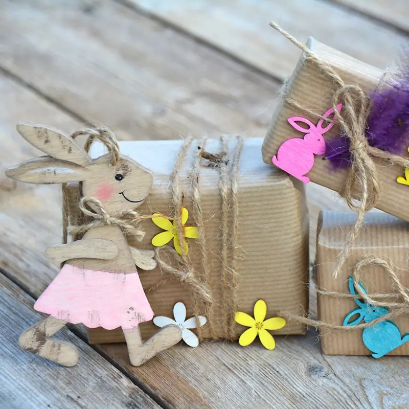 Gift packages in kraft paper with jute ribbon and colorful Easter decorations on a wooden surface.