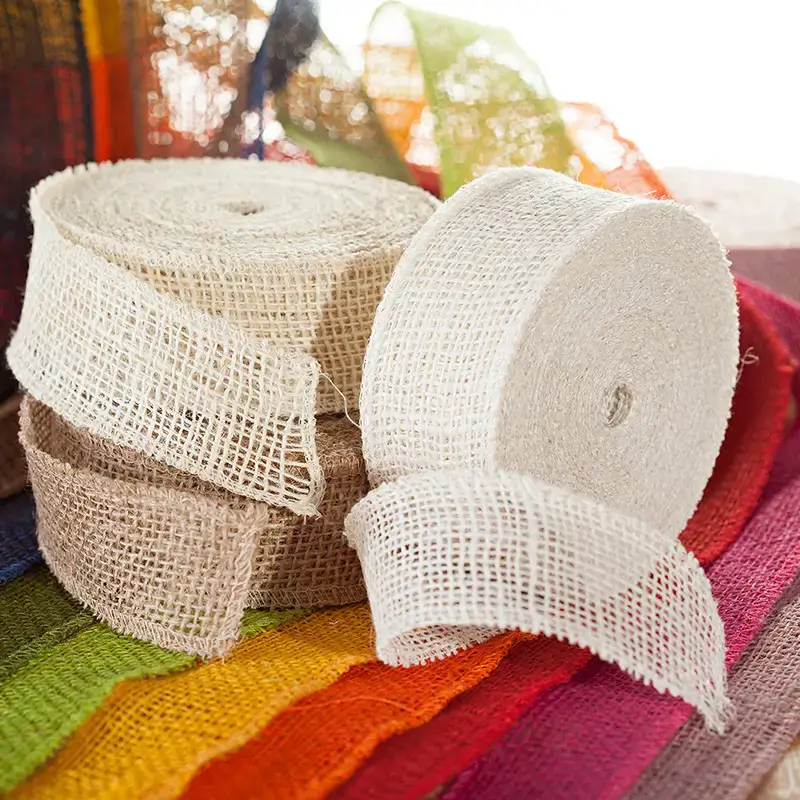 Two rolled-up jute ribbons in natural white and beige on unrolled, colored jute ribbons