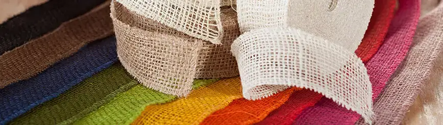 Jute ribbons in various colors, partly rolled up and partly laid out loosely.
